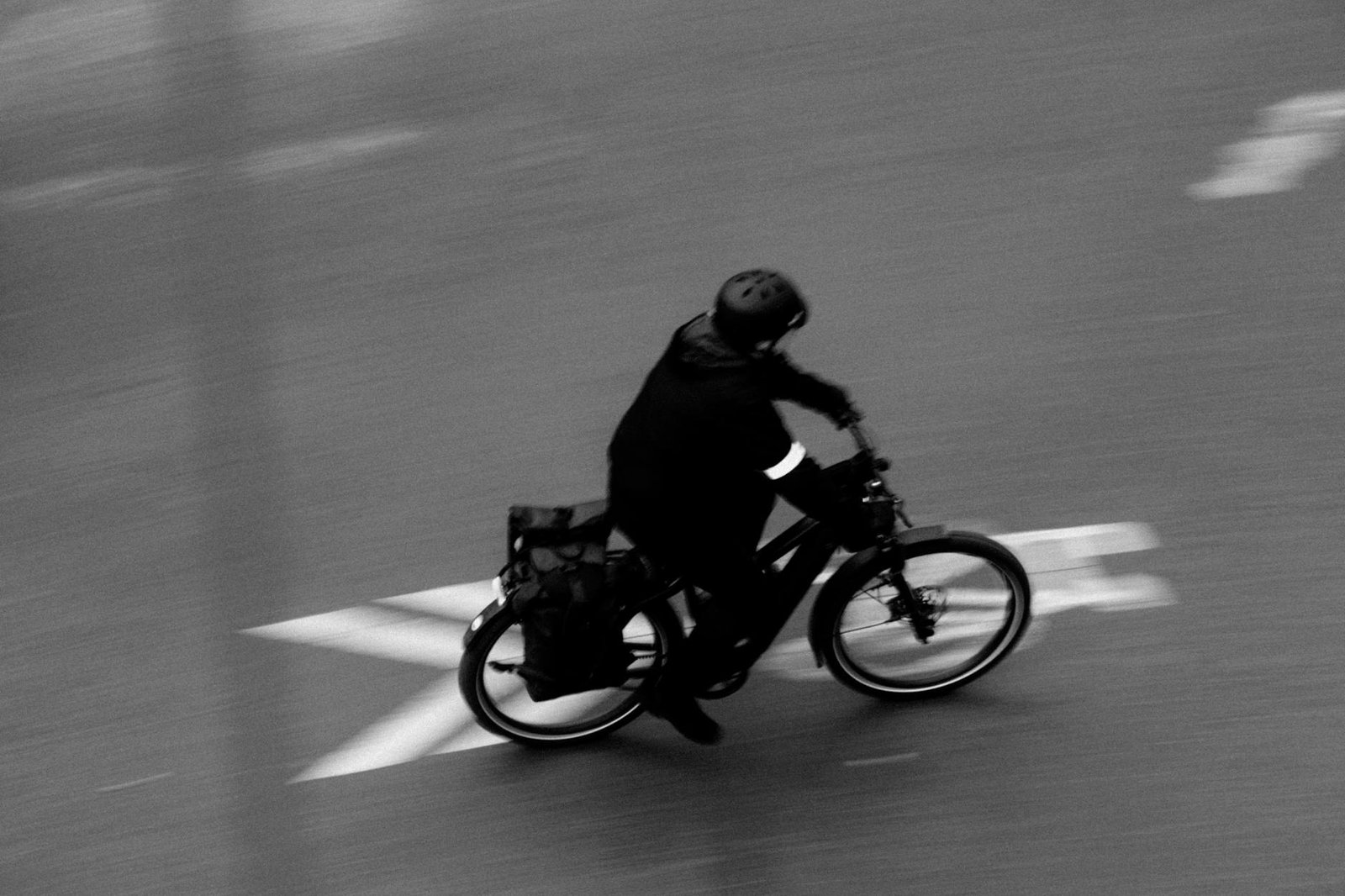A commuter bike near an apartment door with lights, a rain jacket, and a waterproof bag ready for a wet ride.