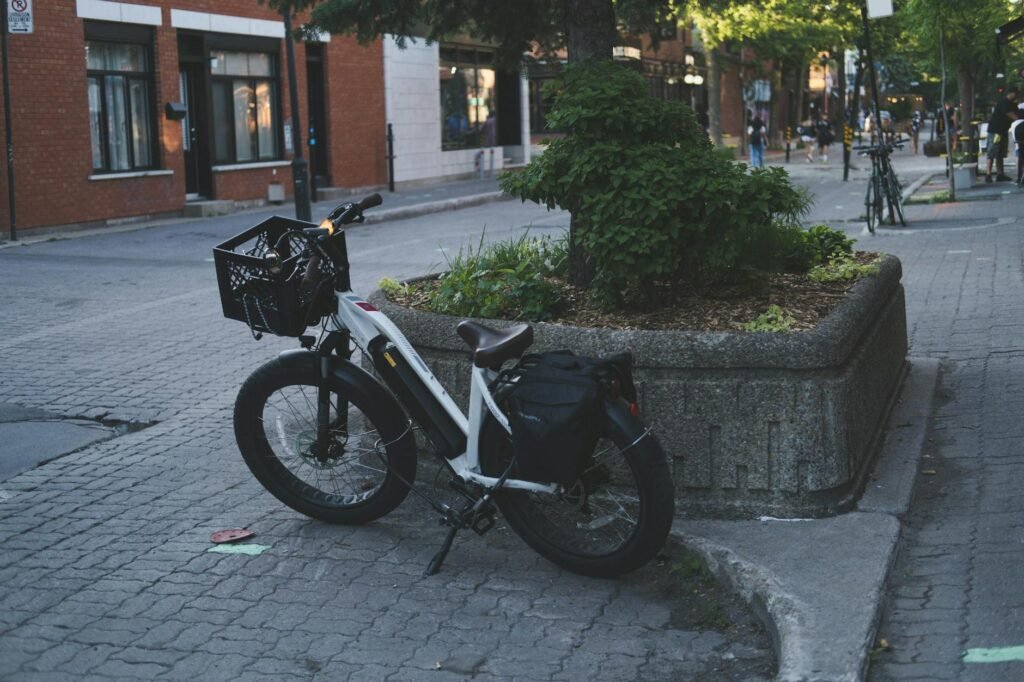 A commuter bicycle with a rear rack and pannier parked outside a modern office building.