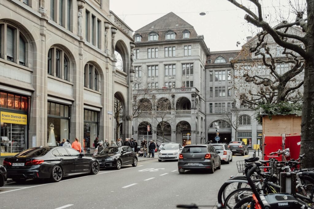 A cyclist riding outside the door zone next to parked cars on an urban street