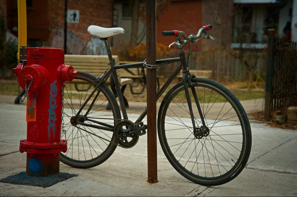A rider locking a commuter bike with a U-lock at a busy bike rack.
