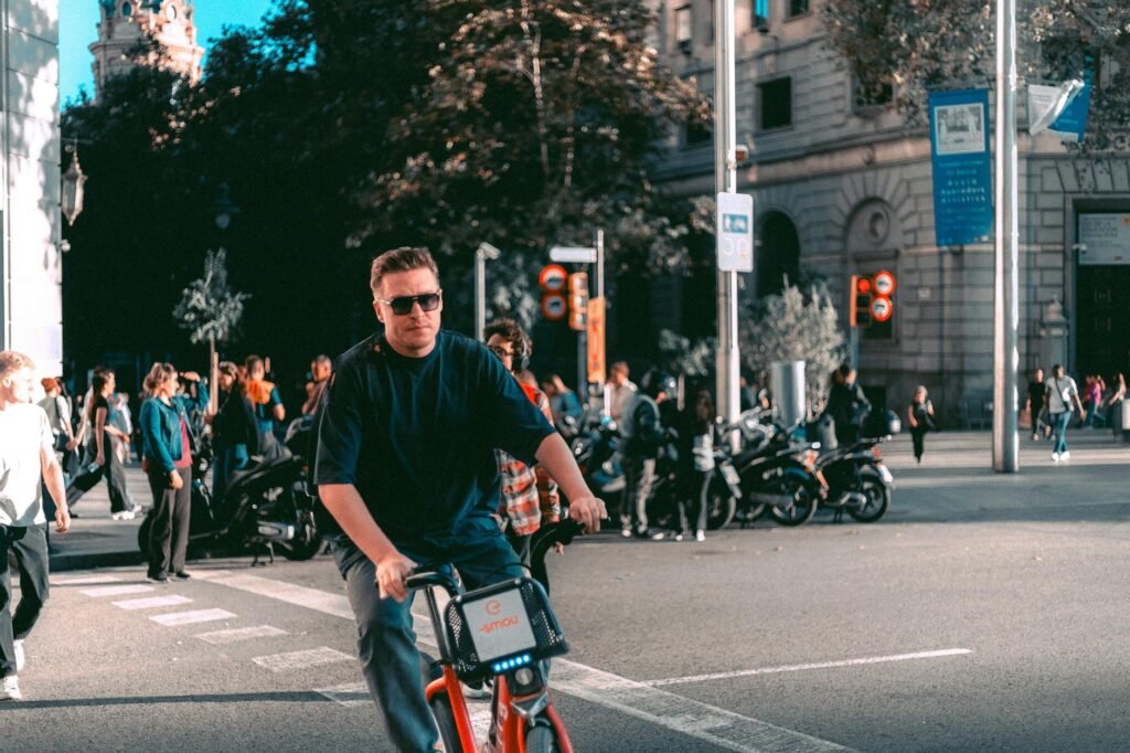 A cyclist approaching a city intersection with parked cars along the curb