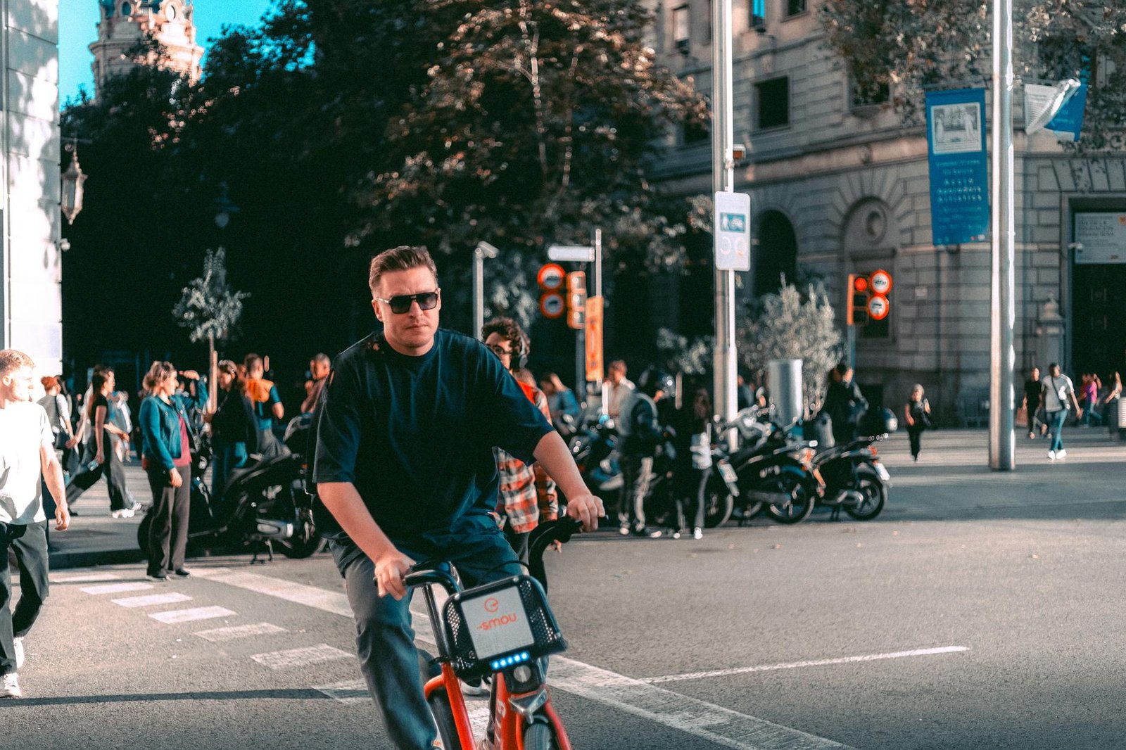 A cyclist approaching a city intersection with parked cars along the curb
