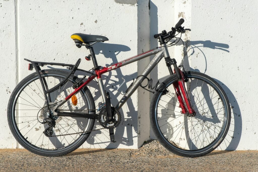 A city commuter bike with fenders, a rear rack, and lights locked to a sidewalk rack.