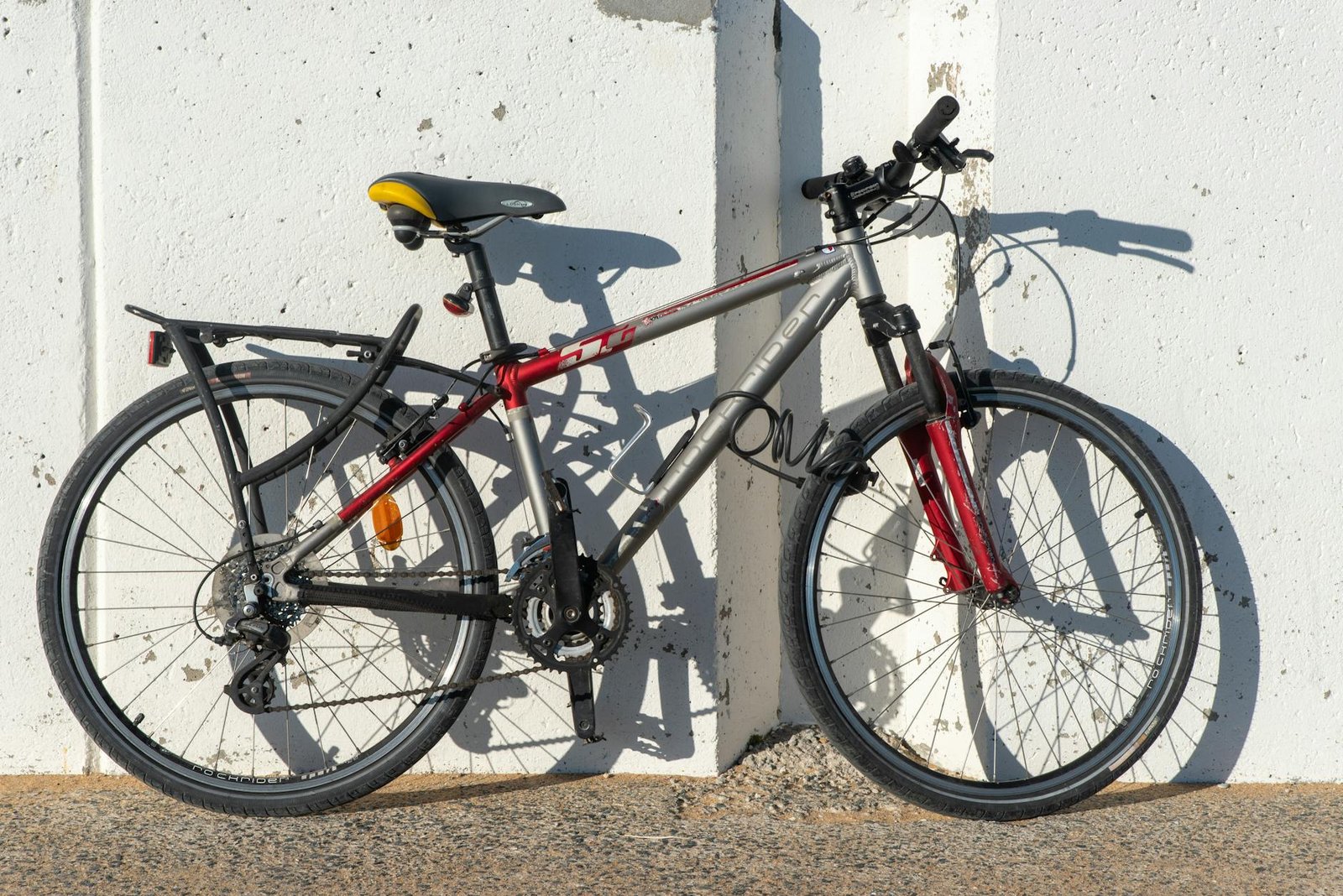 A city commuter bike with fenders, a rear rack, and lights locked to a sidewalk rack.