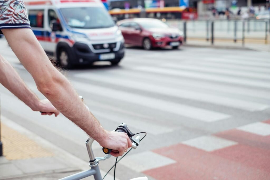 A cyclist stopped behind a large vehicle at a city intersection